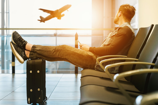 Une personne assise dans un aéroport qui regarde un avion décollé. 