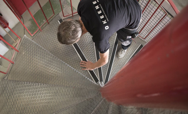 Un poseur de l'équipe d'Okeenea rend les escaliers d'un ERP plus accessibles en installant des nez de marche