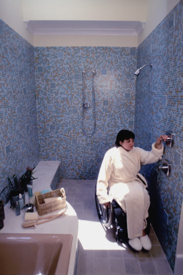 Une femme en fauteuil roulant dans sa salle de bains PMR