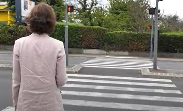 Une femme aveugle traverse un passage piéton grâce au couloir sonore